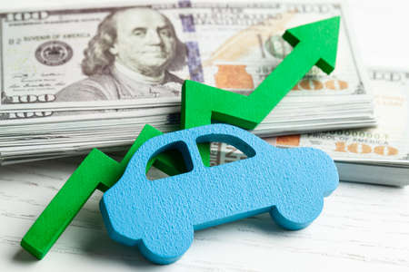 Green arrow graphic up on the background of the car and a stack of money cash dollars. The concept of the growth of the car market, insurance, price growth, repair costsの写真素材