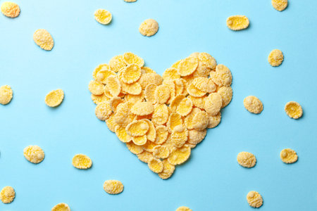 Yellow flakes in the shape of a heart on a blue background. I like breakfast cereal