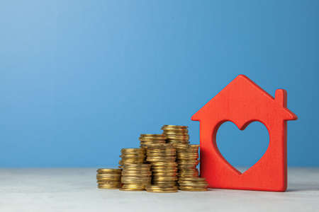 House and stack of coins. The concept of buying home or insurance. Blue background. Copy space for textの写真素材