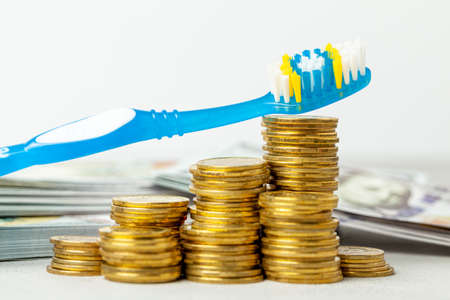 Toothbrush on pile of coins. The concept of expensive dentist or insurance for dentistryの写真素材