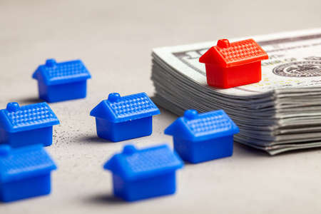 Red house on a stack of money. The concept is expensive and cheap housing. VIP house.の写真素材