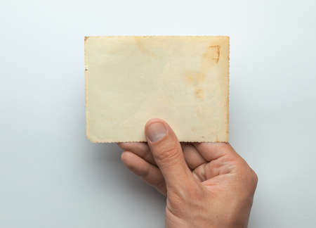 Old photo in the hands of man. Empty template for picture, mock-up. Gray background.の写真素材