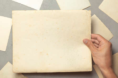 Old photo in the hands of man. Empty template for picture, mock-up. Gray background.の写真素材