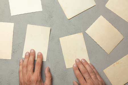 Old photo in the hands of man. Empty template for picture, mock-up. Gray background.の写真素材