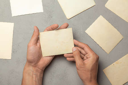 Old photo in the hands of man. Empty template for picture, mock-up. Gray background.の写真素材