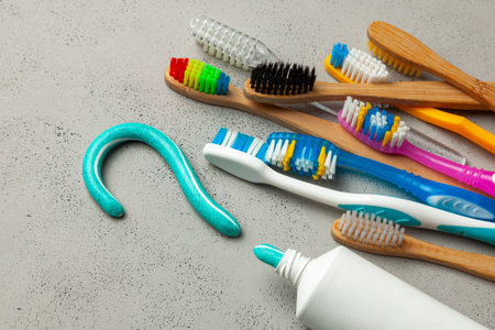 Toothpaste in the form of a question mark and many different and colored toothbrushes. Concept of...