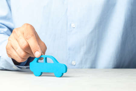 Businessman in shirt holds car in hand. Copy space for textの写真素材
