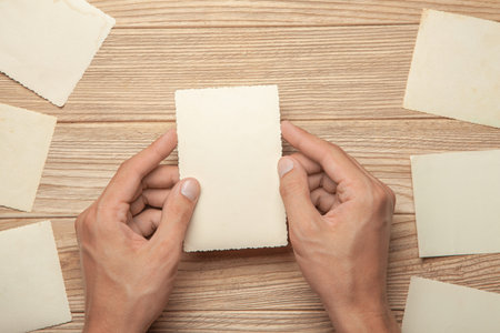 Old photo in the hands of man. Empty template for picture, mock-up. Wooden background.