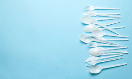 Plastic cutlery, forks, spoons and knives. Pollution of the environment with plastic and microplastics. Blue background. Copy space for text.の写真素材