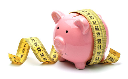 Pink piggy bank and yellow measuring tape isolated on a white background.の写真素材