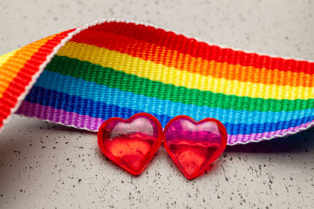 LGBT rainbow ribbon and two hearts. Pride tape symbol. Grey background.の写真素材