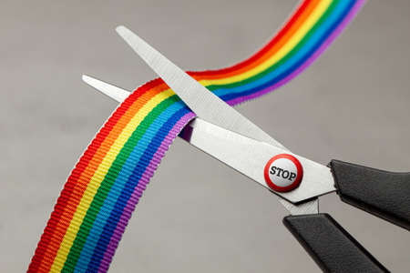Homophobia. STOP LGBT. Prohibition of demonstrations and same-sex marriage. The LGBT rainbow ribbon tape is cut with scissors.の写真素材