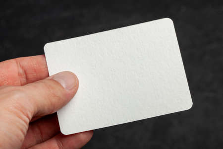 Man holds in his hand a blank template card on black background.の写真素材