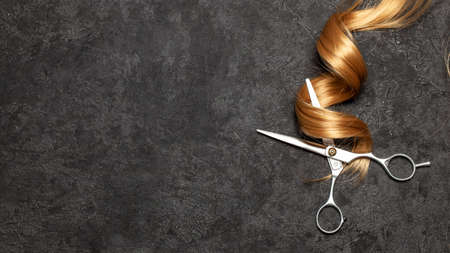 The hairdresser. Scissors and curl of hair on a black background.の写真素材