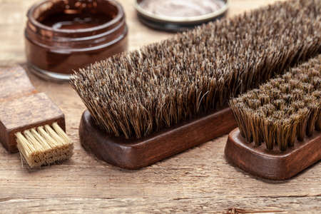 Brush for shoes. Cleaning and polishing shoes with brushes. Shoe polish and brush on wooden backgroundの写真素材