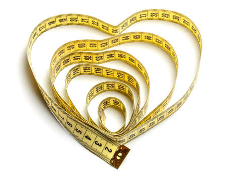 Heart made of yellow measuring tape isolated on white backgroundの写真素材