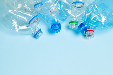Crumpled plastic bottles on a blue background. Plastic trash. Copy space for text.