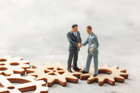 Hiring staff. Selection of the leader of the manager for the company. Businessmen in suits shake hands on gears as a symbol of business processes in the companyの写真素材