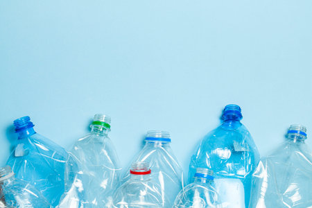 Crumpled plastic bottles on a blue background. Plastic trash. Copy space for text.
