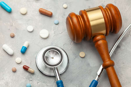 Judge gavel and stethoscope with pills. The law in medicine, the sentence on medical negligence.の写真素材