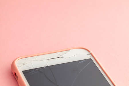 Broken phone with crack on the display glass on pink background. Copy space for text.の写真素材