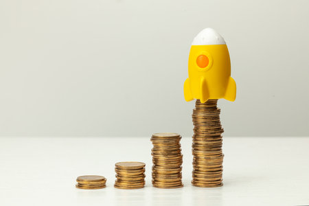 Rocket and stack of gold coins on gray background. Profit growth conceptの写真素材