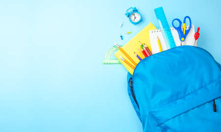 School bag. Backpack with supplies for school on blue background. Copy space for textの写真素材