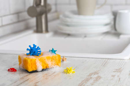 Sponge for washing dishes with viruses and microbes on the background of the kitchen and plates.の写真素材