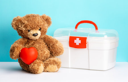 Teddy bear with heart and first aid kit on green backgroundの写真素材