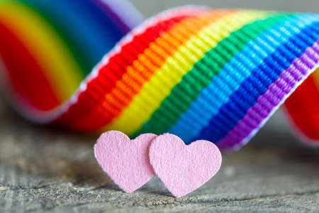 Two pink hearts as a symbol of lesbian love. Rainbow ribbon background in the colors of the LGBT community flagの写真素材