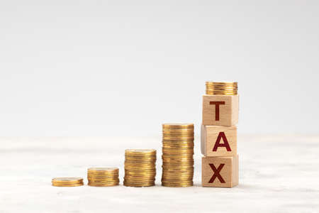 Stack of gold coins and the inscription TAX. Progressive taxes. Wealth tax.の写真素材