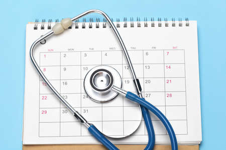 Calendar and stethoscope on a blue background. The concept of a planned examination by a doctorの写真素材