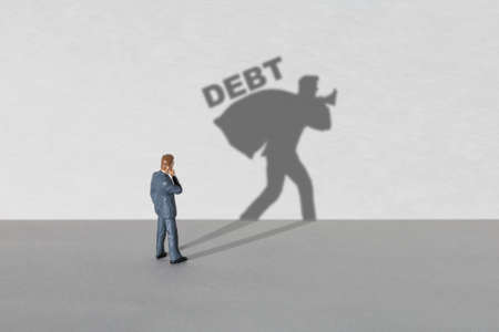 Debt businessman. Businessman thinks but the shadow shows debtの写真素材