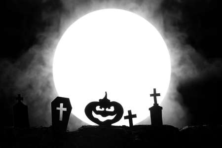Halloween. Cemetery with graves and pumpkin on the background of the moon with fogの写真素材
