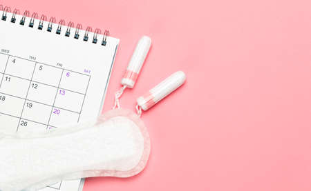 Menstruation calendar. Calendar with pads and tampons on a red background. Template Copy space for text. mock-upの写真素材
