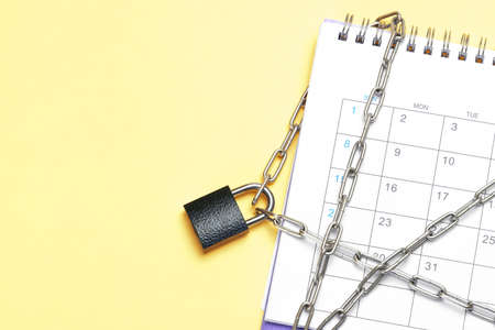 Calendar is wrapped in a chain and closed with a padlock. Yellow background. Template Copy space for text. mock-upの写真素材