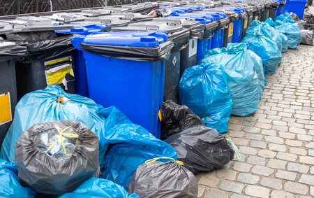 Garbage on the streets of the city. Plastic containers for garbage. Garbage sorting. Black and blue garbage bags.の写真素材