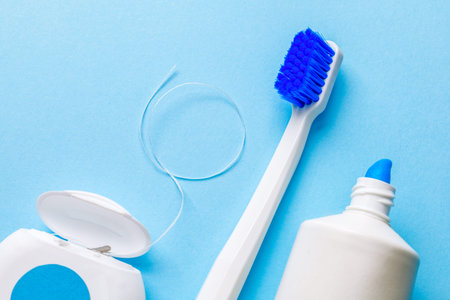 White toothbrush with toothpaste and dental floss on a blue background.の写真素材