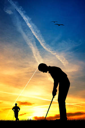 man playing golf at sunsetの写真素材