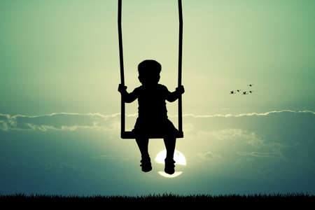 child on swing ilhouette at sunsetの写真素材