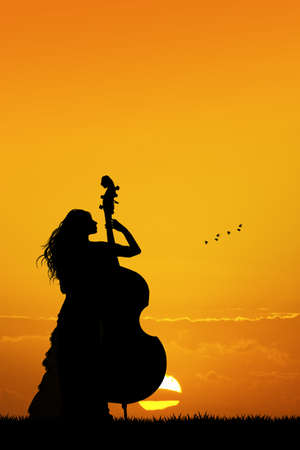 woman plays the double bass at sunsetの写真素材
