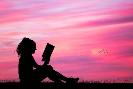 girl reading a book at sunsetの写真素材
