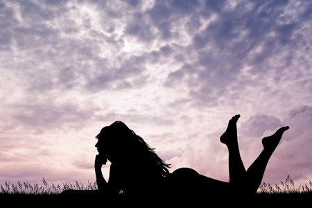 girl lying on grass at sunsetの写真素材