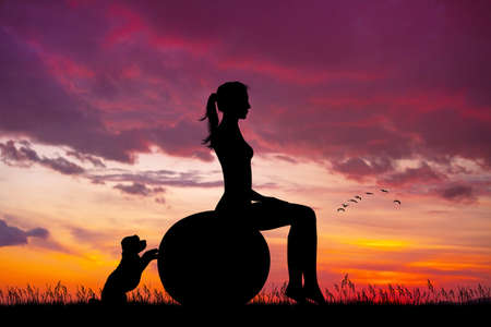 girl does pilates at sunset with her puppyの写真素材