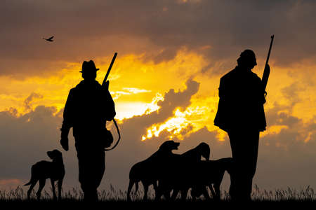 hunters with dogs at sunsetの写真素材