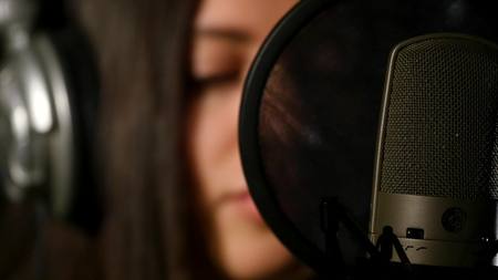 Female singer in headphones against microphone.の写真素材
