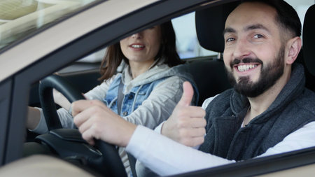 Visiting car dealership. Beautiful family is talking and smiling while sitting in their new car....
