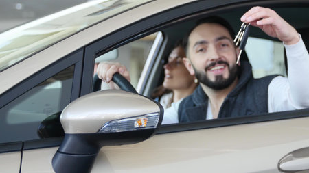 Visiting car dealership. Beautiful family is talking and smiling while sitting in their new car....