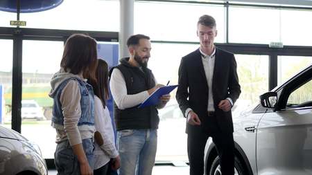 Car salesman shows a young family information about their new car.の写真素材