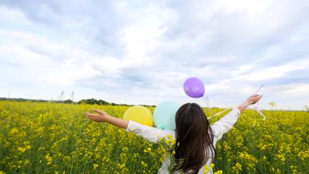Happy Little Girl Playing with Soap Bubbles, Balloons on Meadow, Smiling Child Relaxing on rape field, Slow Motion.の写真素材